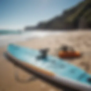 An array of paddleboarding equipment displayed on a sandy beach under a clear blue sky