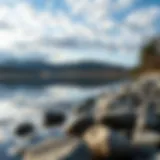 A serene lake reflecting the sky with perfectly smooth stones along the shore